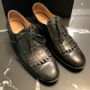 Salvatore Ferragamo Oxford black leather with fringe detailing and gold accents.
